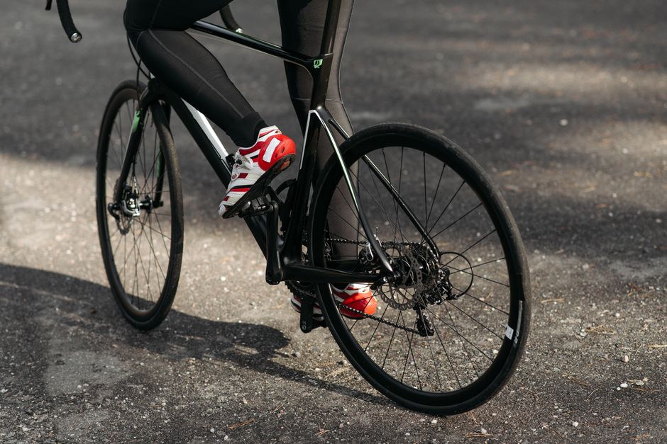 Close-up of cyclist's feet in red cycling shoes on a road bike pedal, illustrating foot stress during summer cycling in Boise.